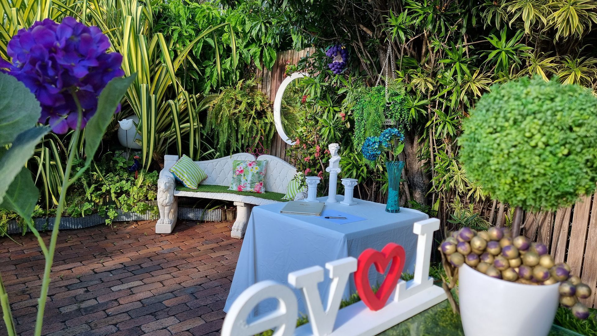 A Garden With Purple And White Flowers And A White Umbrella — Wayne & Adele's Garden of Eating BYO Restaurant In South Townsville, QLD