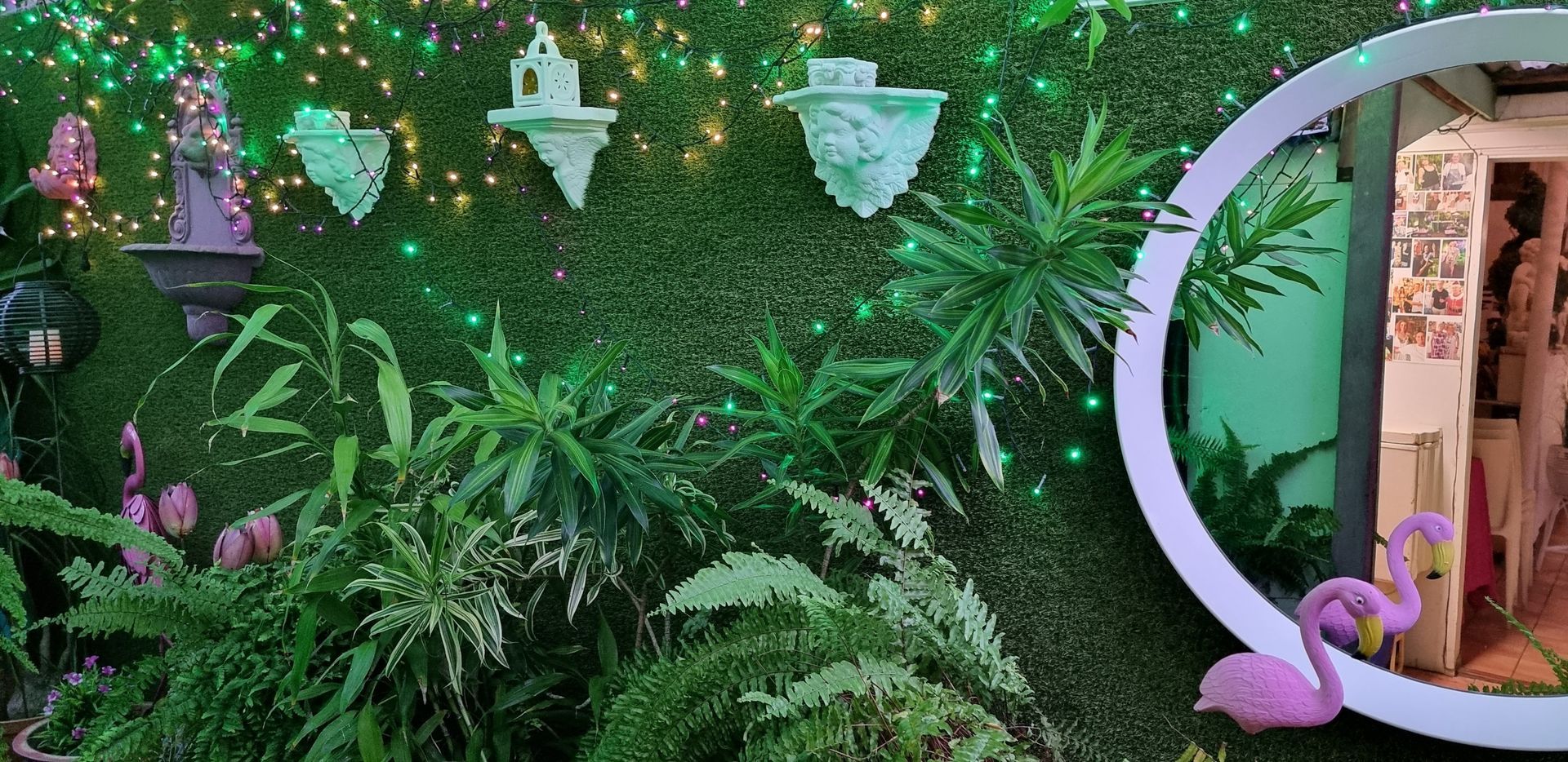 A green wall with plants and a pink flamingo in front of it  — Wayne & Adele's Garden of Eating BYO Restaurant In South Townsville, QLD
