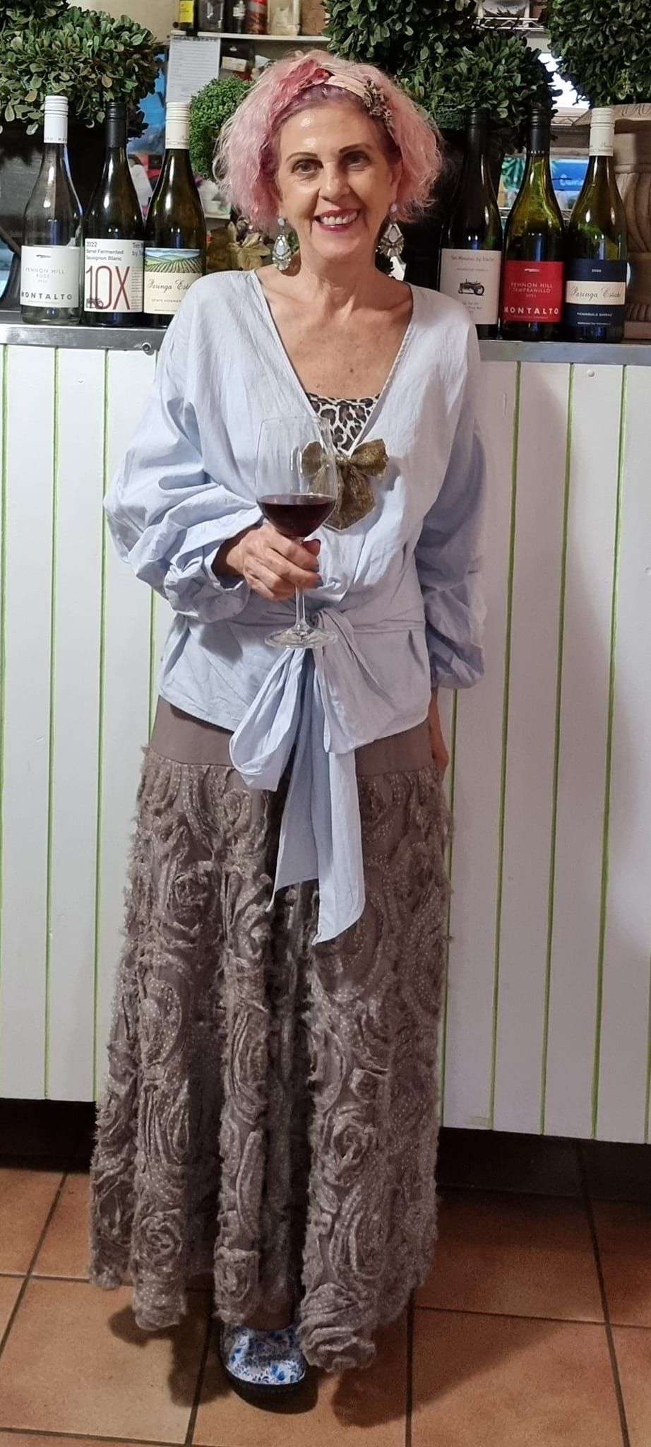 A woman is standing in front of a bar holding a glass of wine  — Wayne & Adele's Garden of Eating BYO Restaurant In South Townsville, QLD