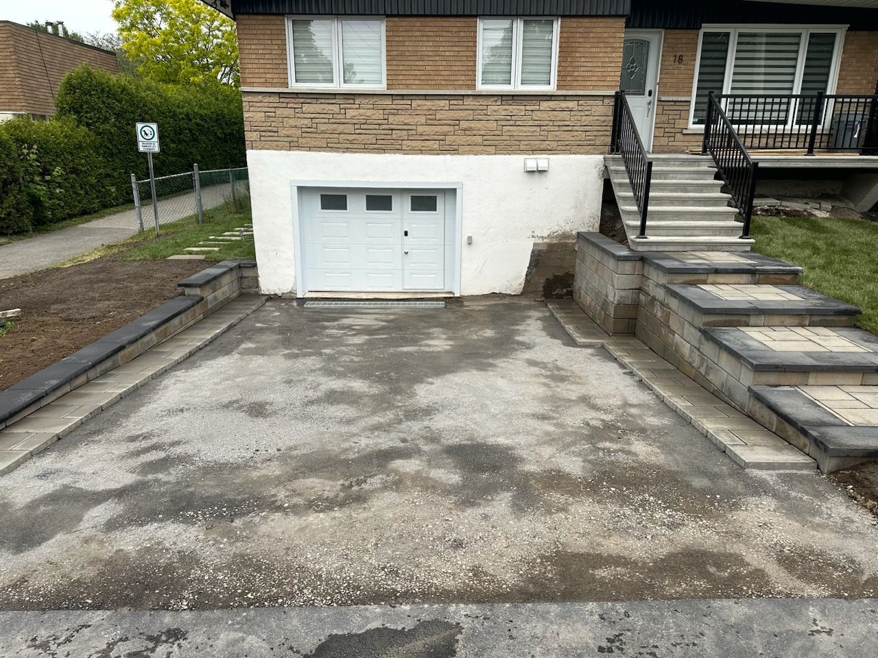 Une allée menant à une maison avec escalier et un garage.