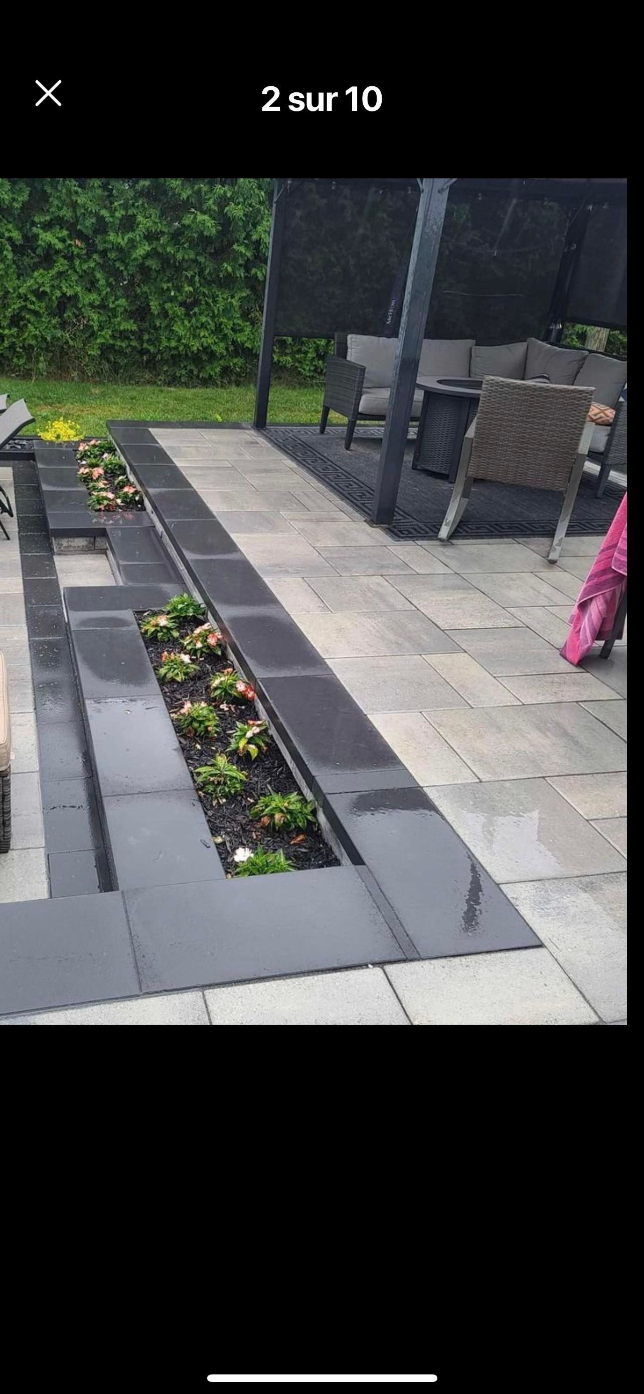 Une personne se tient sur une terrasse à côté d'une jardinière remplie de plantes.