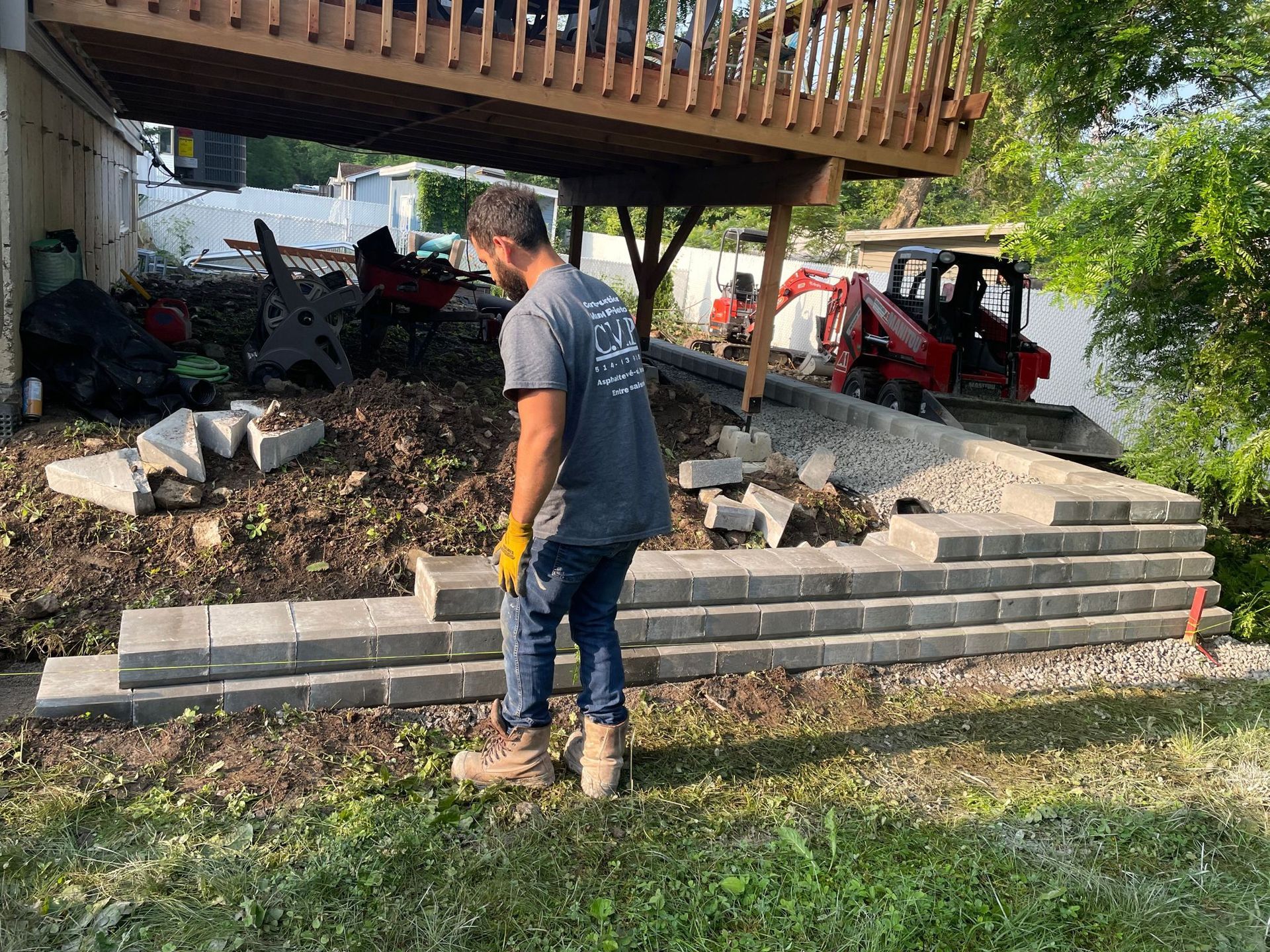 Un homme se tient à côté d'un tas de briques sous une terrasse.