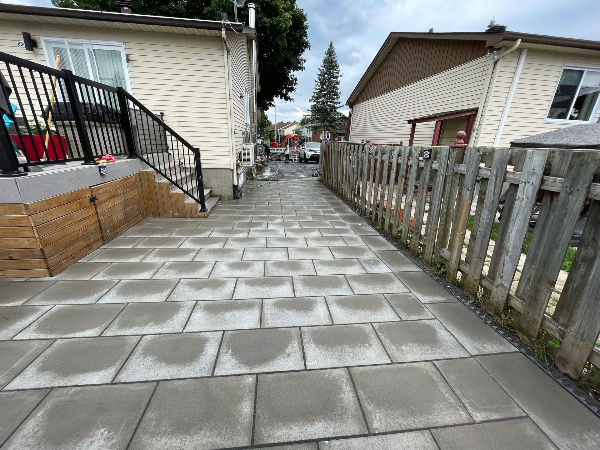 Une allée en briques menant à une maison avec une clôture en bois.