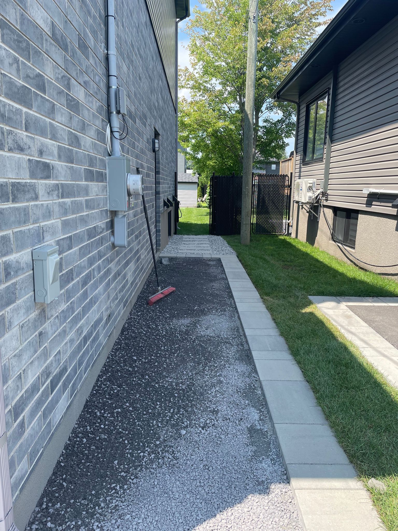 Un trottoir menant à une maison à côté d'un mur de briques.