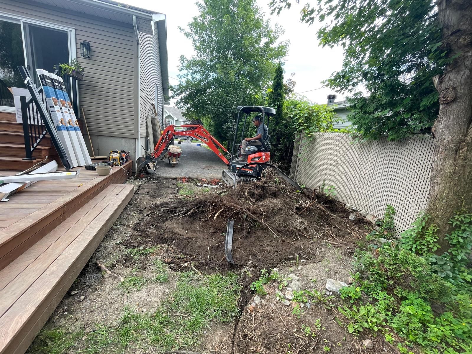 Une excavatrice creuse un trou dans l'arrière-cour d'une maison.