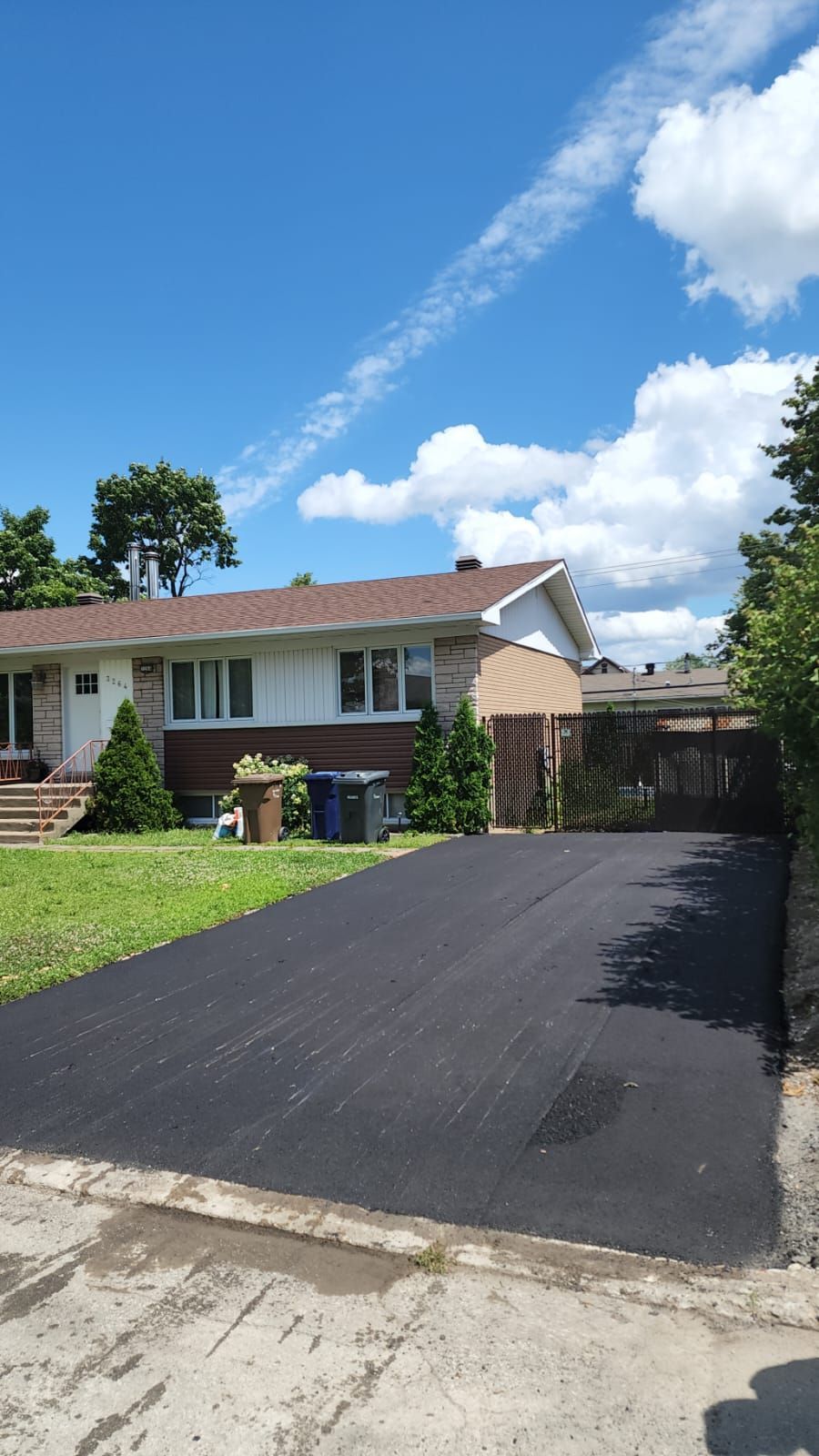 Une maison avec une allée devant elle par une journée ensoleillée.