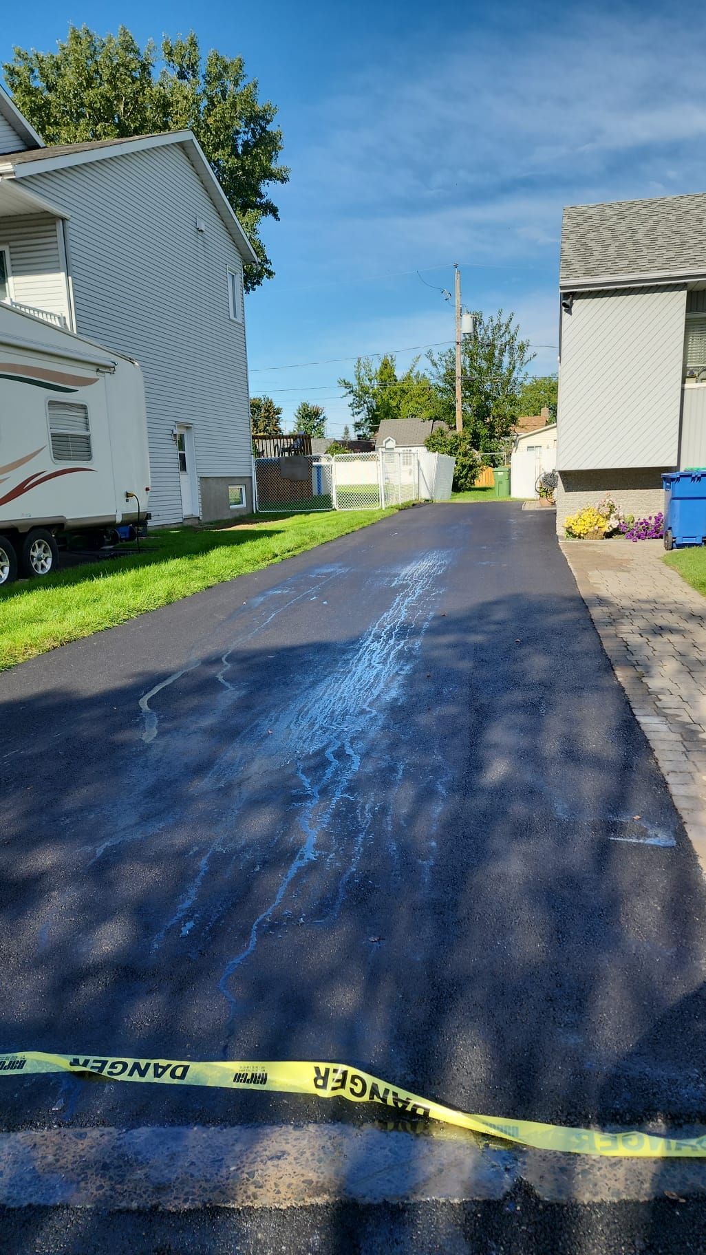 Une allée nouvellement pavée dans un quartier résidentiel à côté d'une maison.