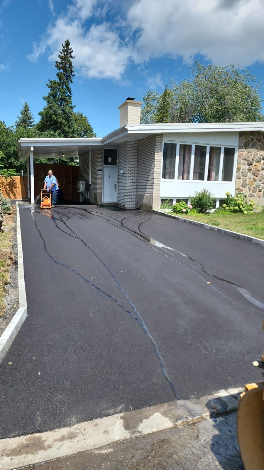 Un homme utilise un aspirateur pour nettoyer une allée devant une maison.