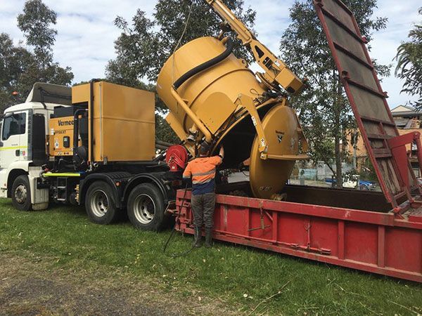 A man is standing next to a large yellow truck.