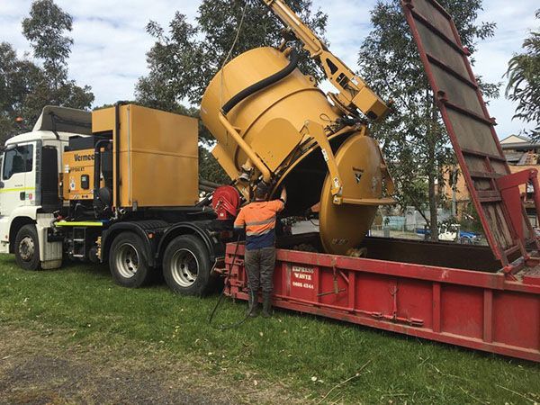 A man is standing next to a large yellow truck.