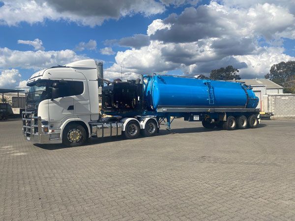 A white truck with a blue tank on the back is parked in a parking lot.