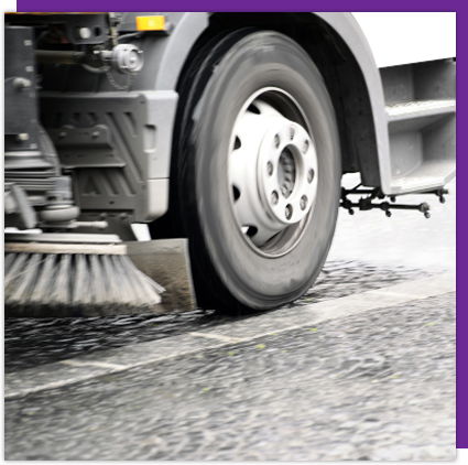 A truck is cleaning the street with a broom.