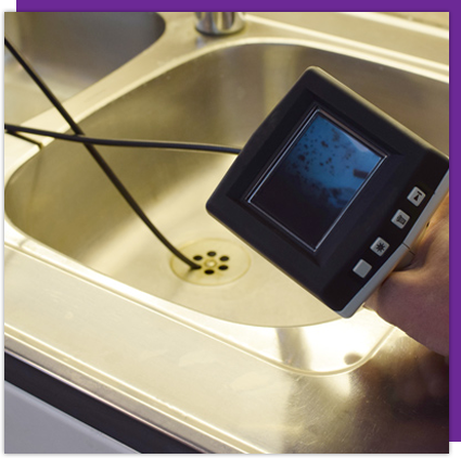 A person is holding a camera over a sink