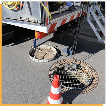 A manhole cover on the side of the road next to a truck