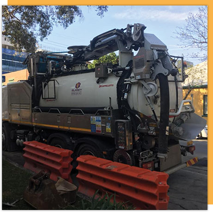 A vacuum truck is parked on the side of the road