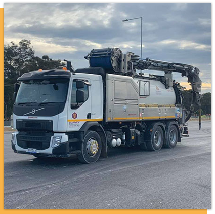 A manhole cover on the side of the road next to a truck