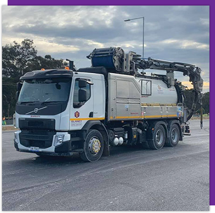 A vacuum truck is parked on the side of the road.