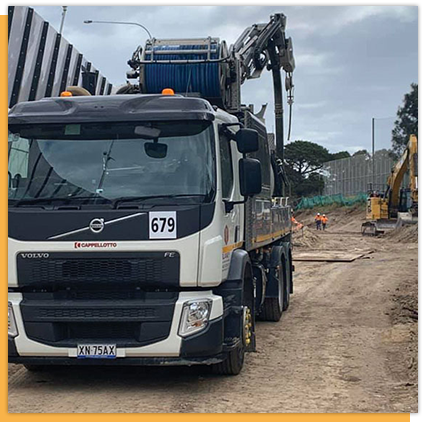 A volvo truck with a crane on top of it is parked on a dirt road.