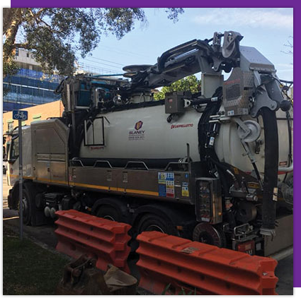 A vacuum truck is parked on the side of the road