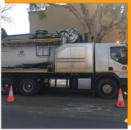 A large tanker truck is parked in front of a building