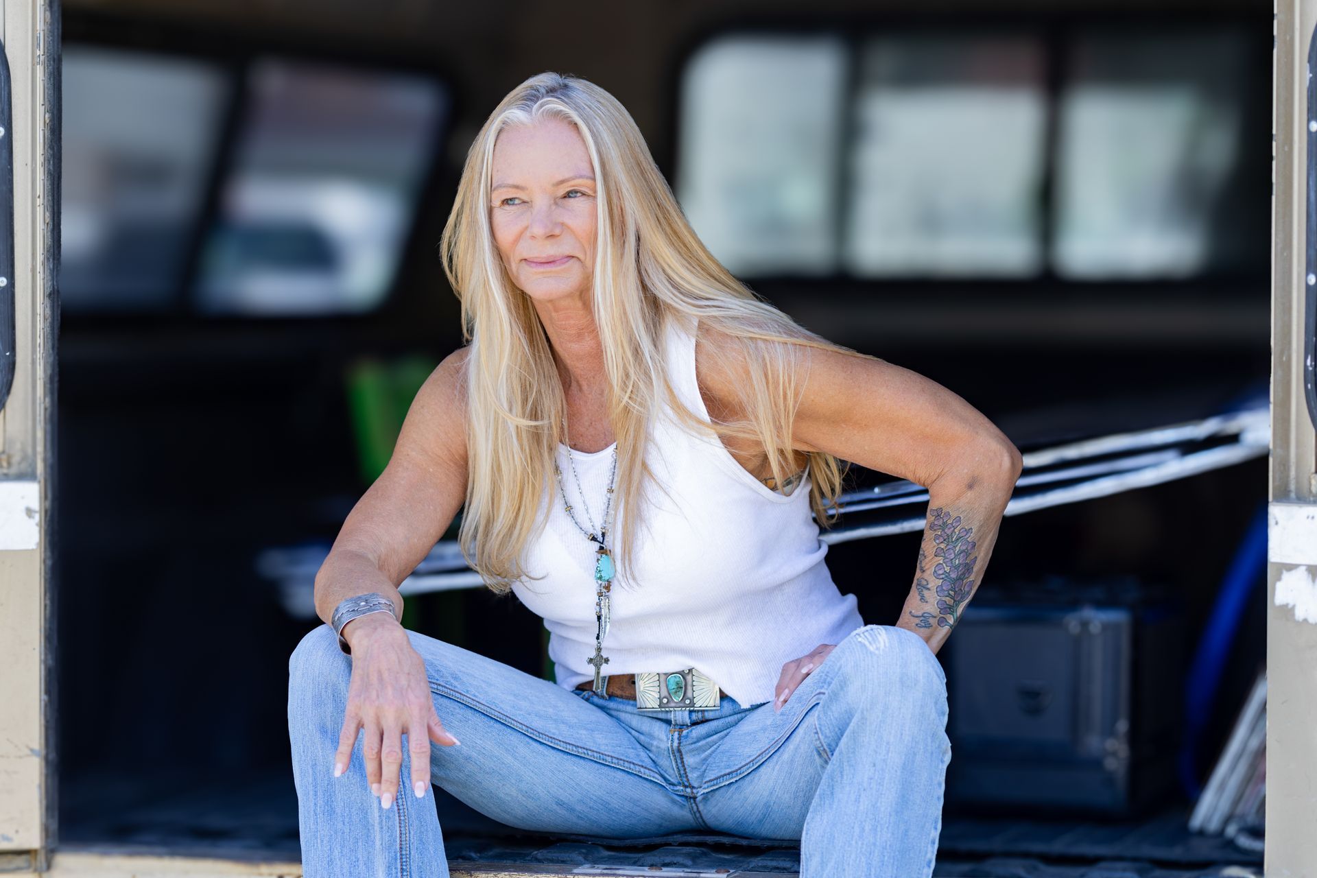 A woman is sitting on the doorstep of a truck.