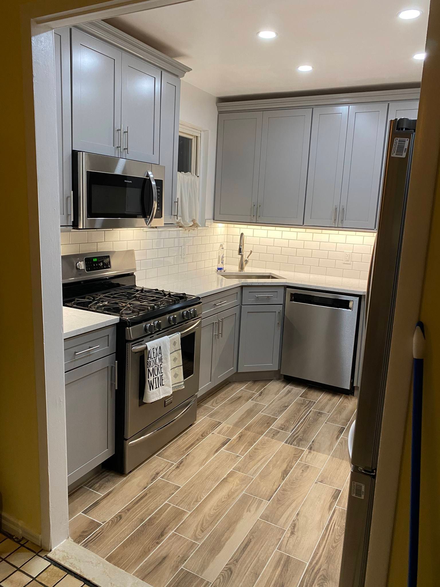 Renovated kitchen with gray cabinets, stainless steel appliances, and wood-look flooring.