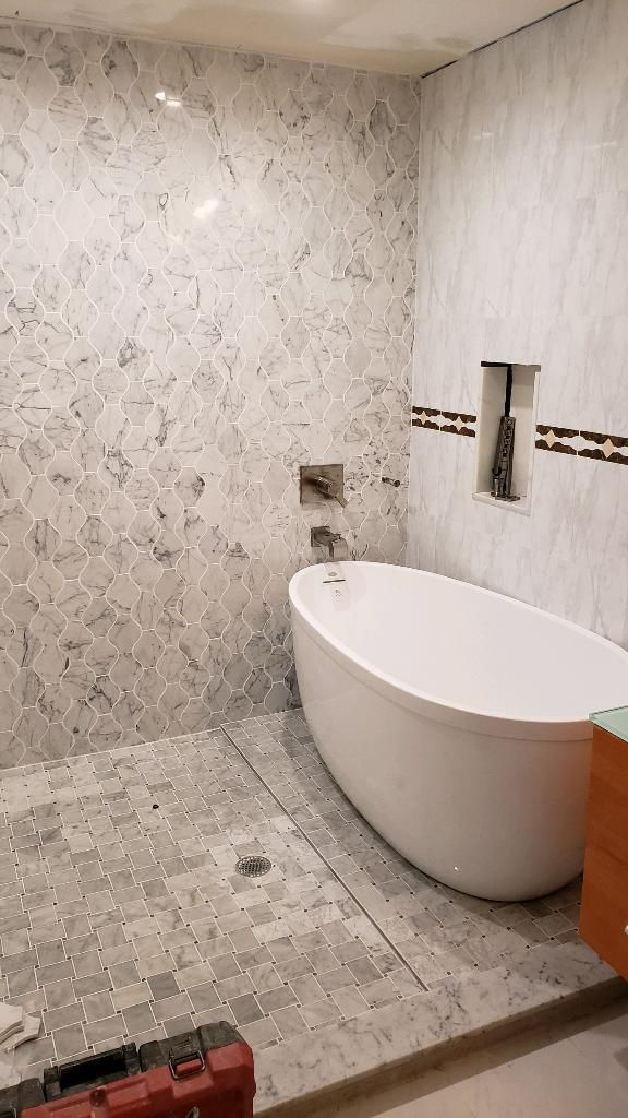 Bathroom with white freestanding tub, marble tile walls and floor.