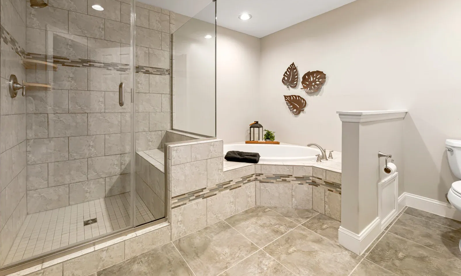 Bathroom with a glass shower, a built-in tub, and a toilet. Neutral tones, modern decor.
