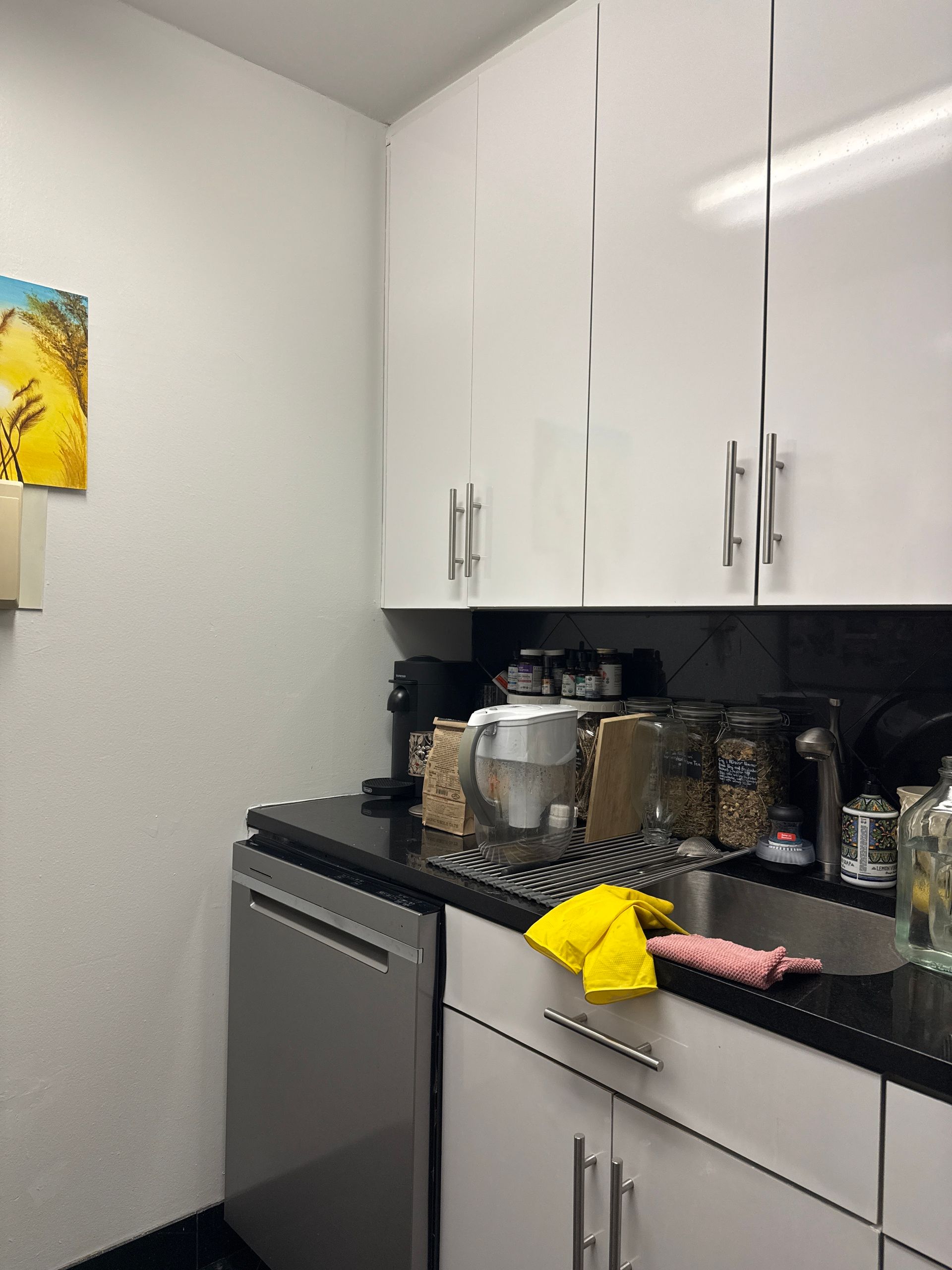 Small kitchen with white cabinets, black countertop, and stainless steel appliances.