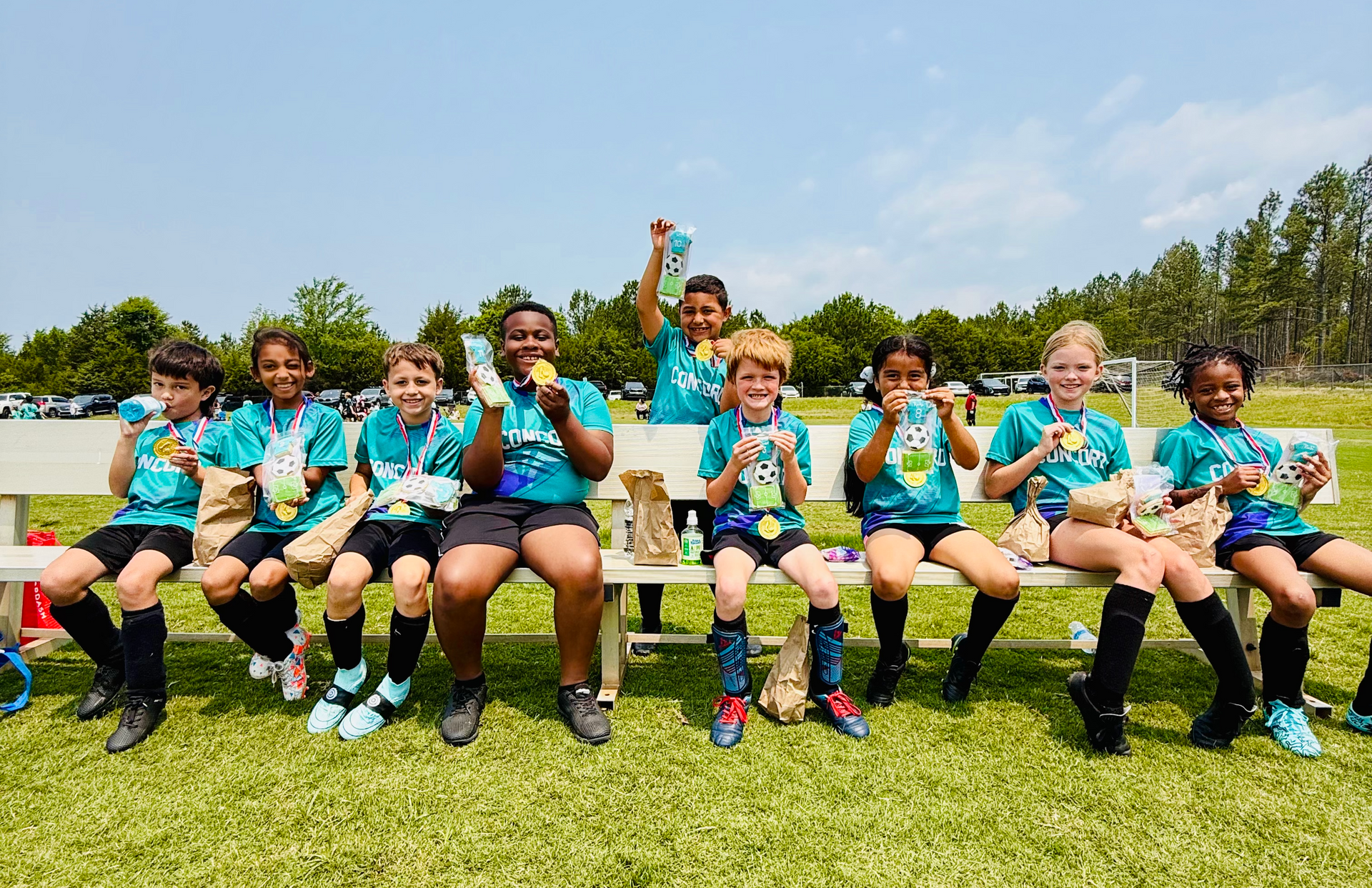 Two boys with arms around each other, smiling outdoors. One in a gray "Track and Field" shirt, the other in stripes.