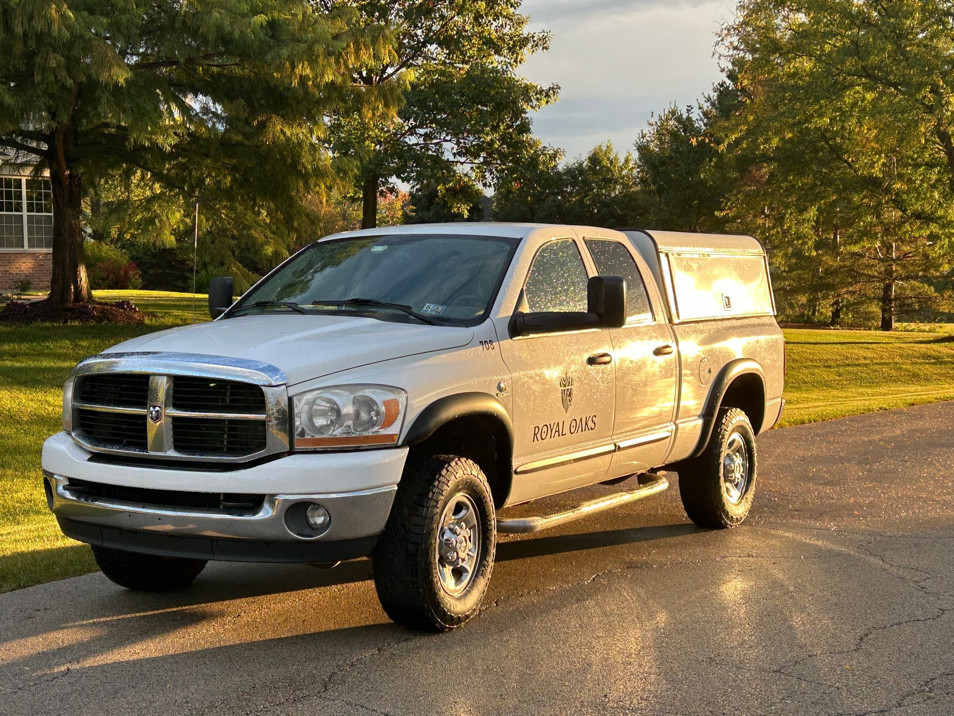 A team of tree service workers in lime green shirts poses with a truck and American flag on a lawn.