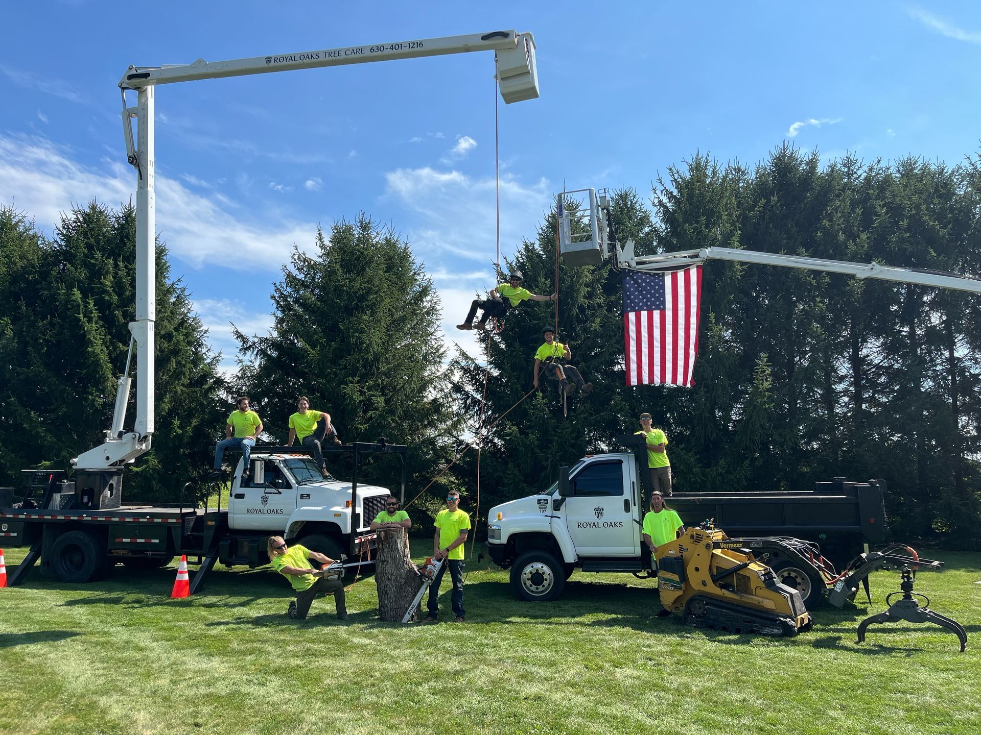 A group of construction workers are posing for a picture in front of their trucks.
