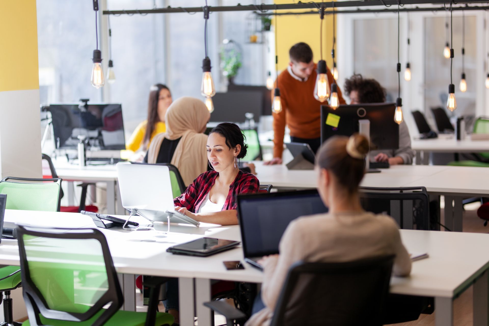 People working at desks with computers in an open-plan office setting.