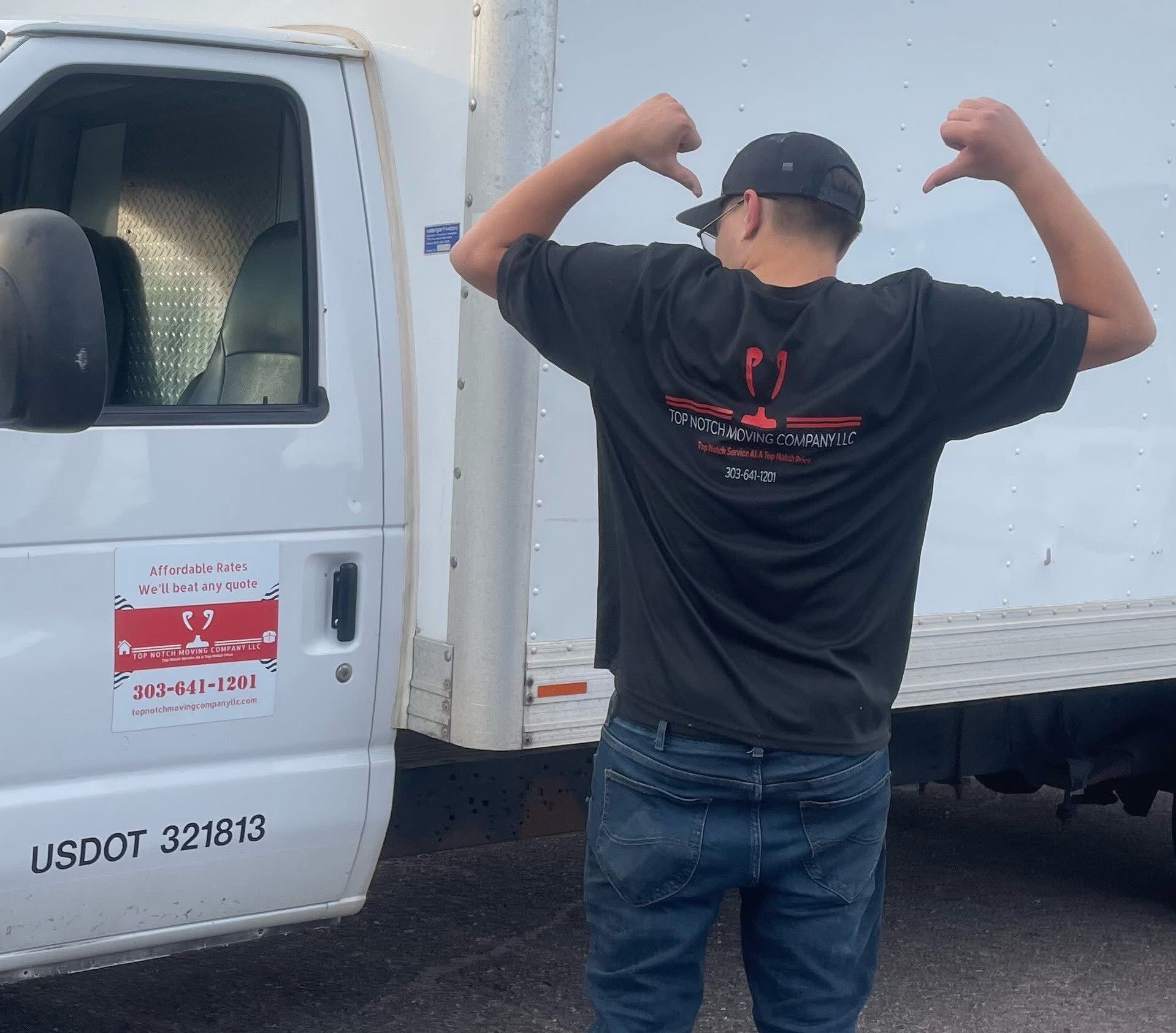 Man in black shirt with thumbs down next to white truck.