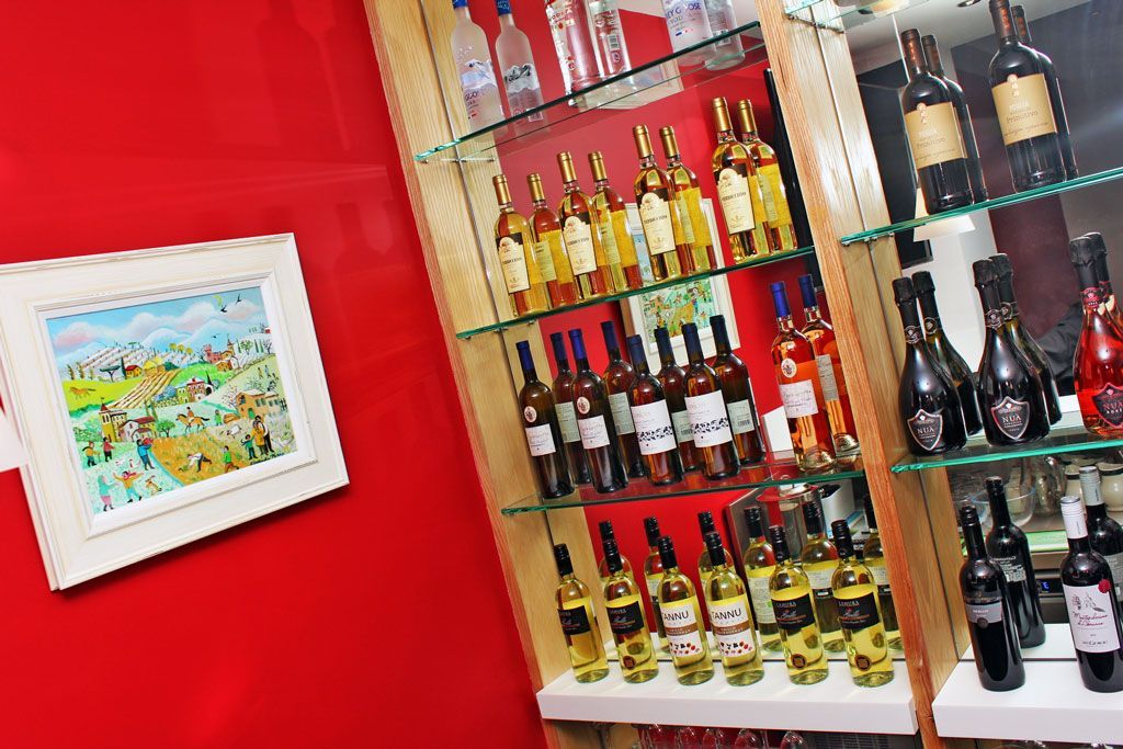 A shelf filled with bottles of alcohol and a painting on the wall