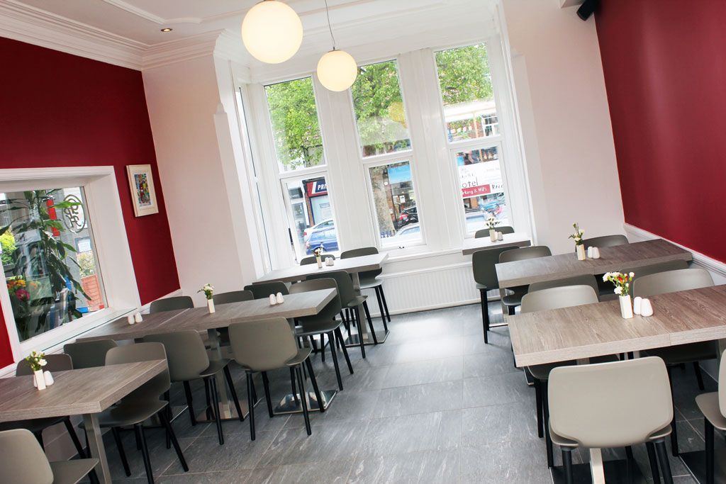 A restaurant with tables and chairs and a red wall.