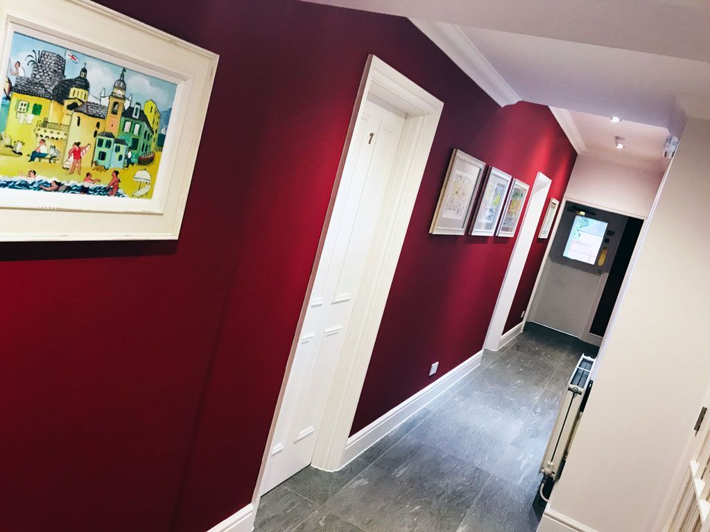 A hallway with red walls and a picture on the wall.