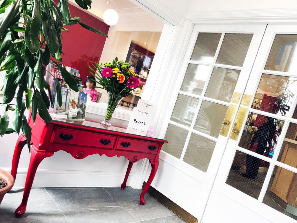 A red table with a vase of flowers on it in a room.