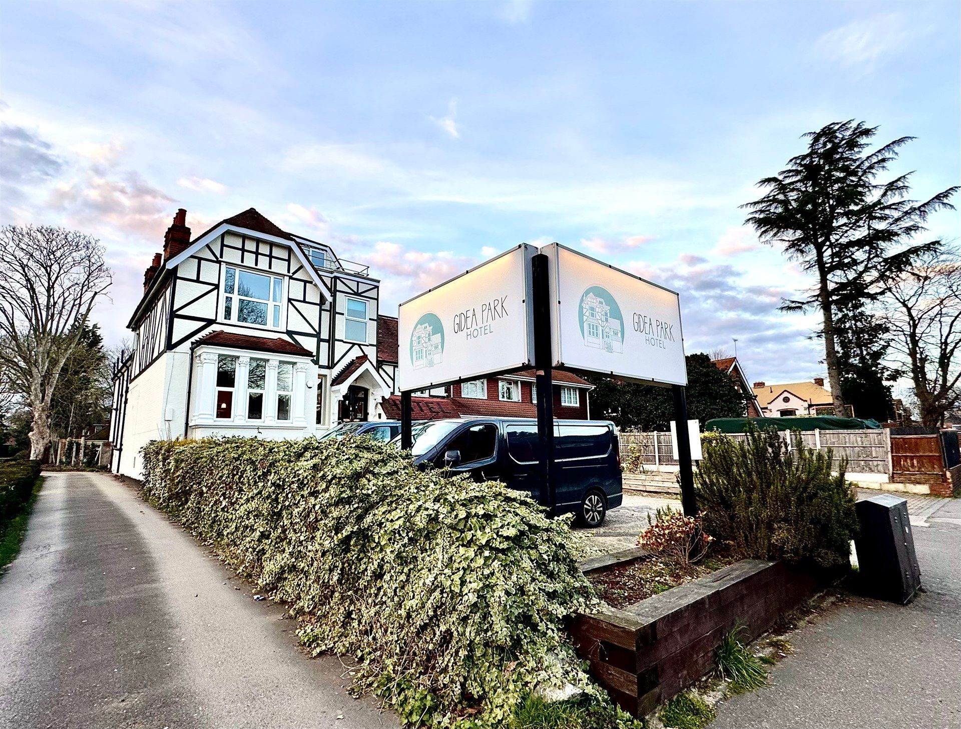 A large house with a sign in front of it and a car parked in front of it.