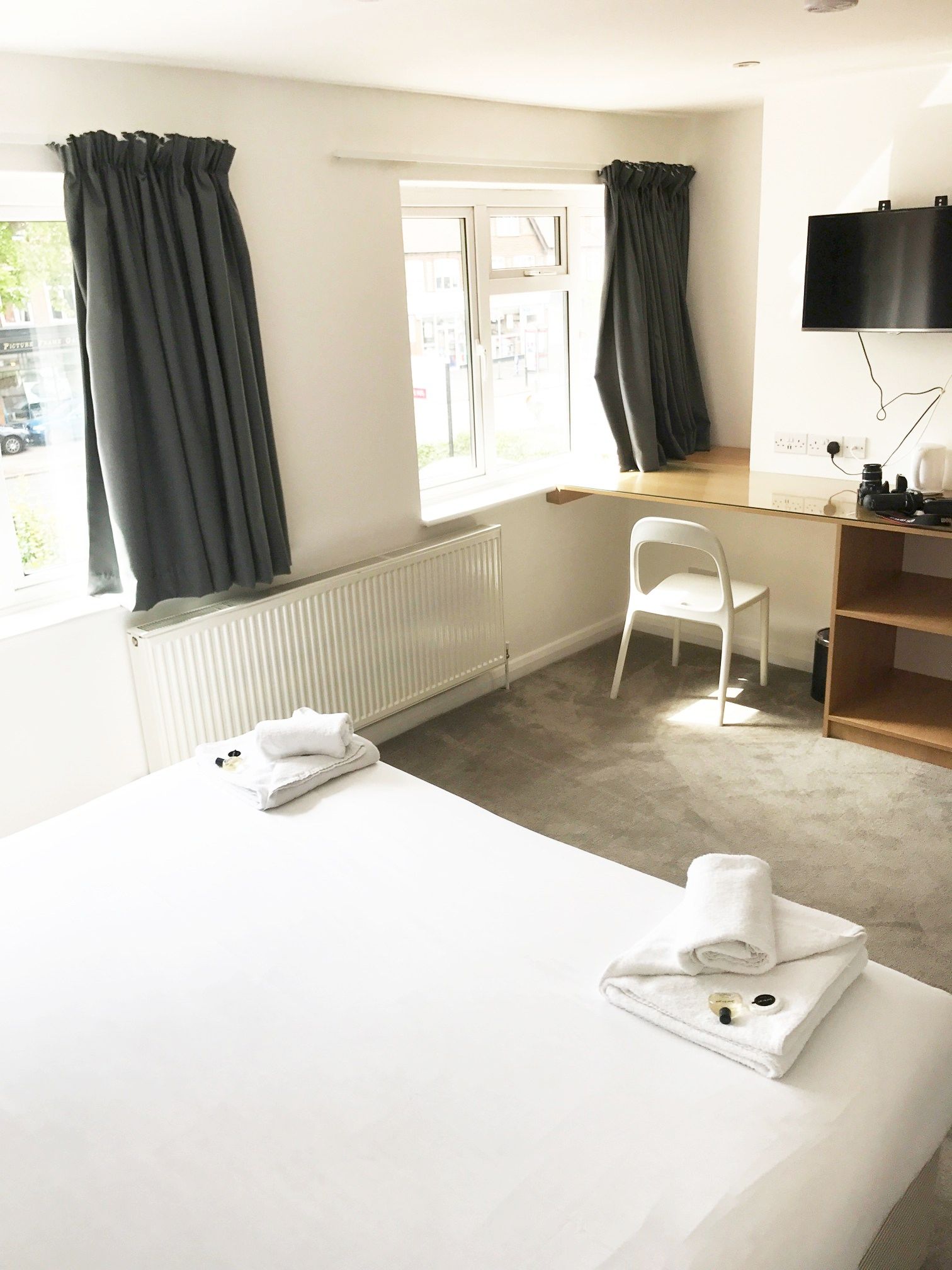 A hotel room with a bed , chair , desk and window.