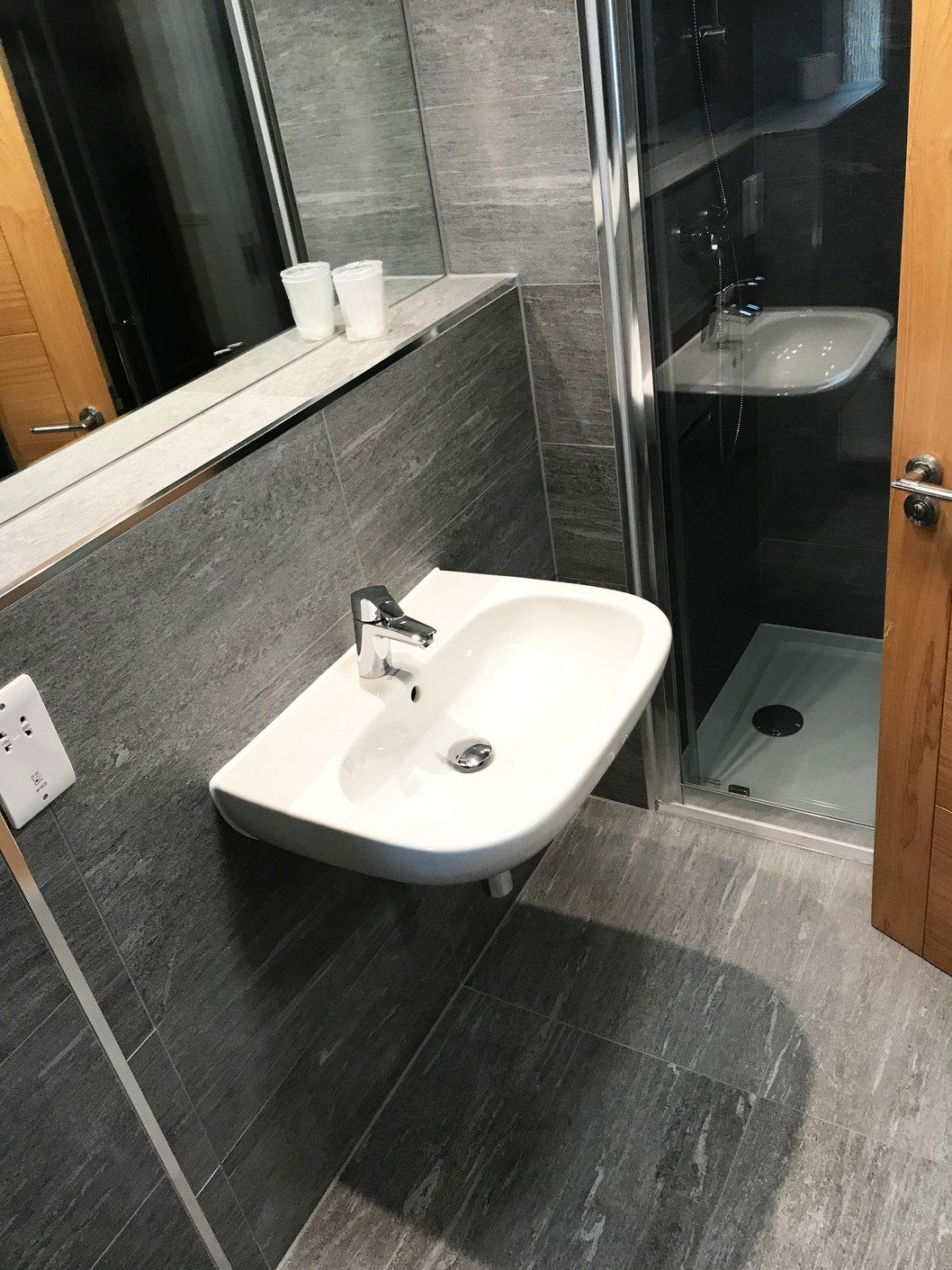 A bathroom with a sink , shower and mirror.