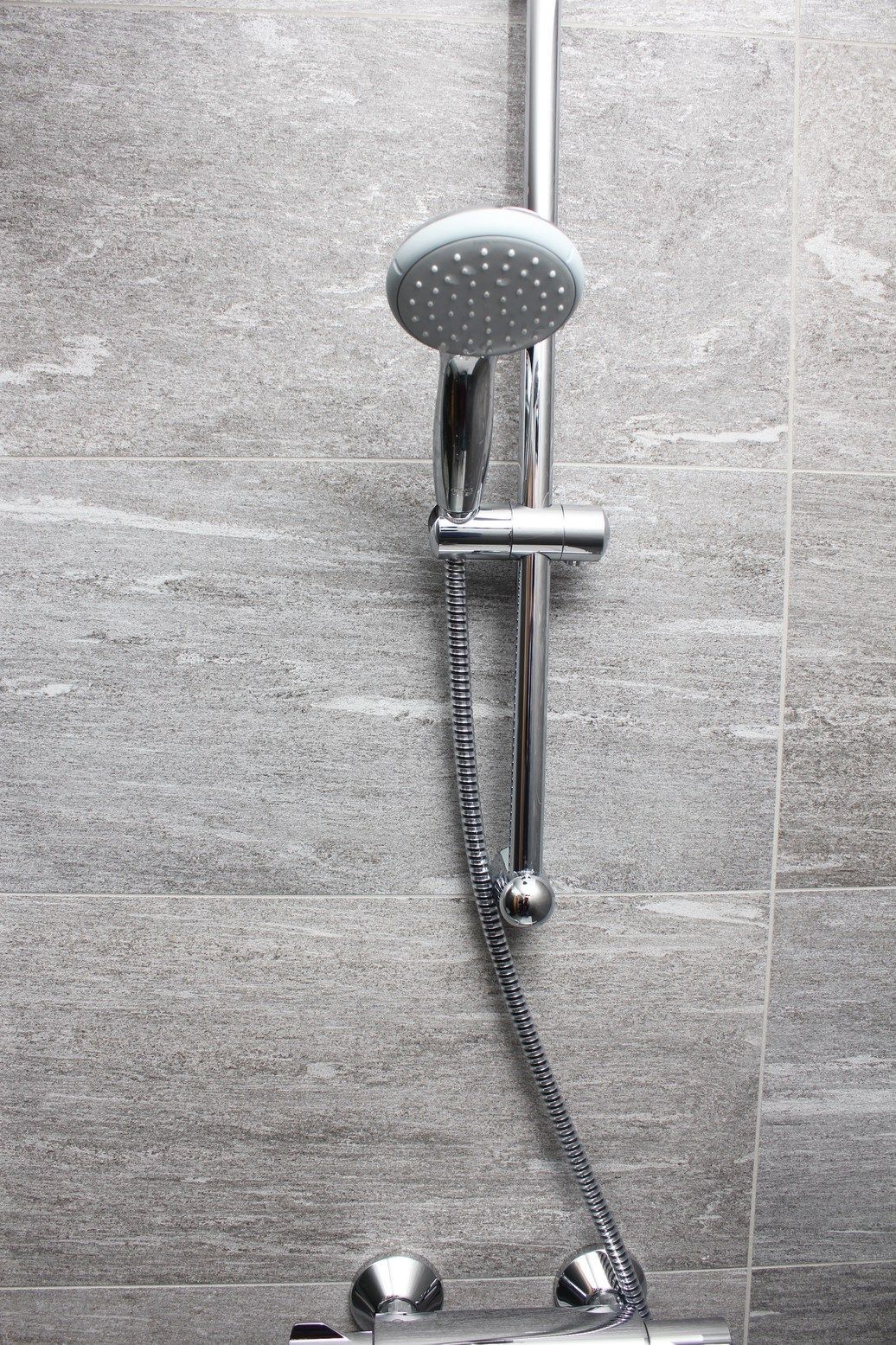 A close up of a shower head and hose in a bathroom.