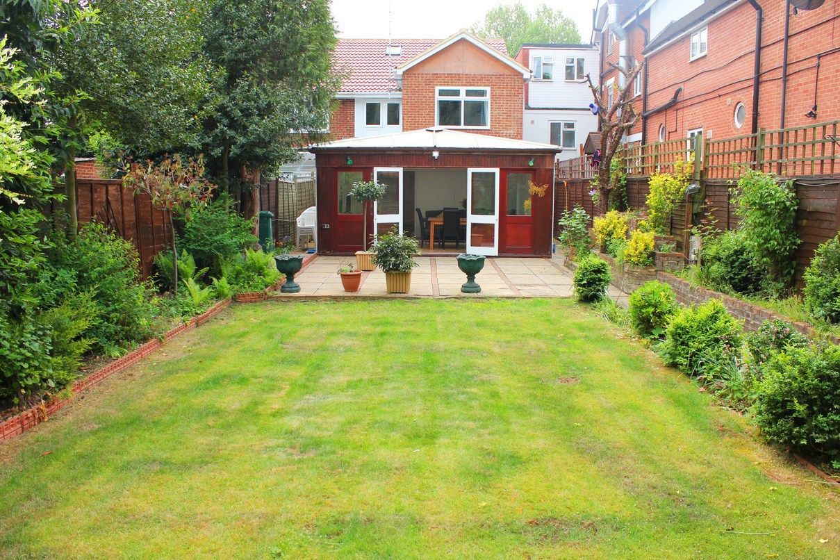 A large lush green lawn in front of a brick house.