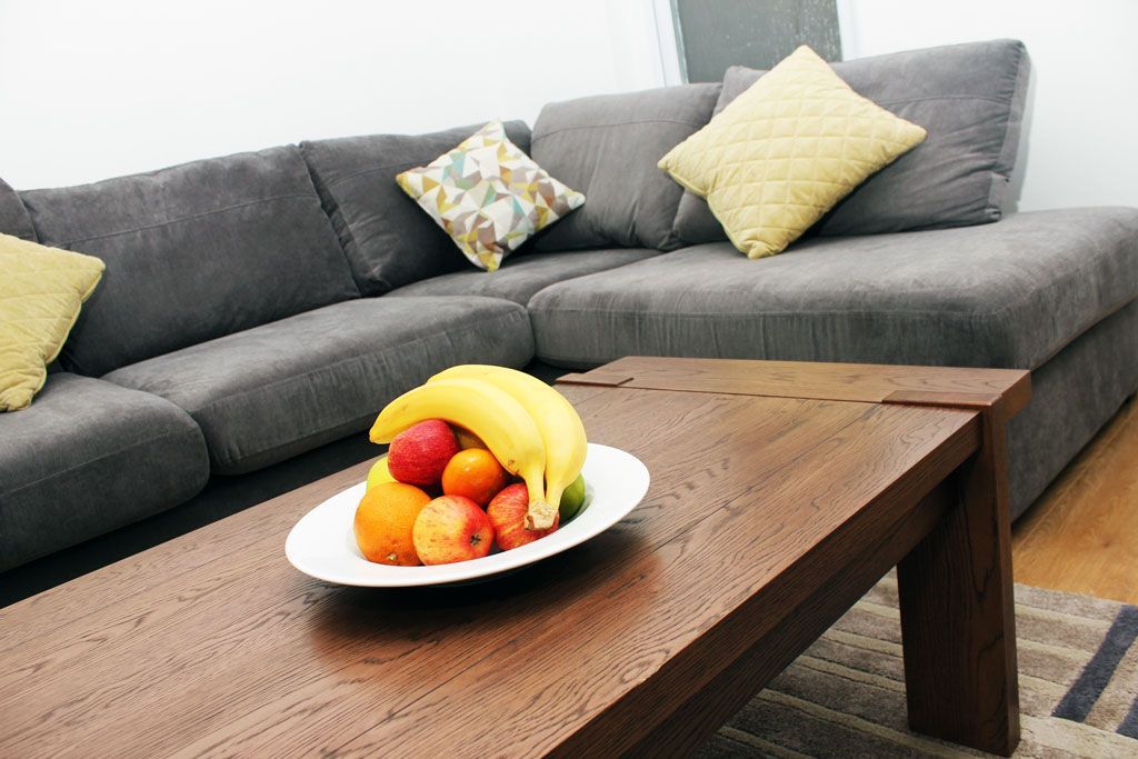 A bowl of fruit sits on a coffee table in front of a couch.