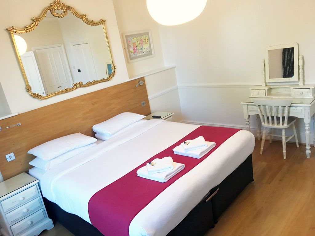 A hotel room with a large bed and a dresser