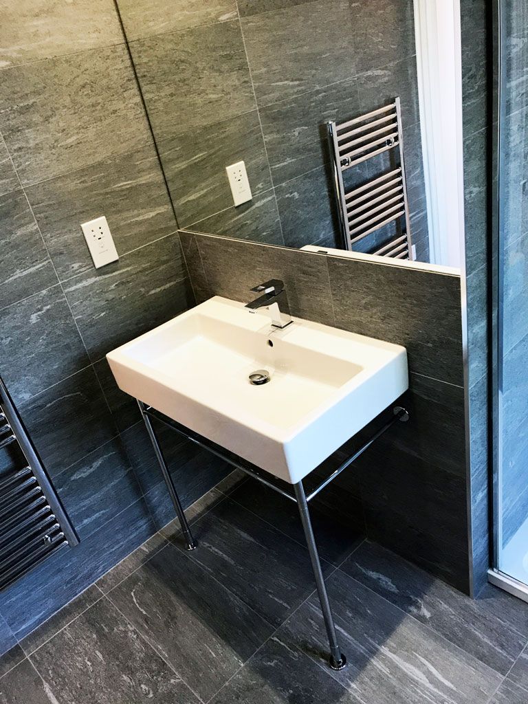 A bathroom with a sink , mirror and towel rack.