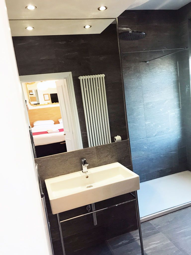 A bathroom with a sink , mirror and walk in shower.