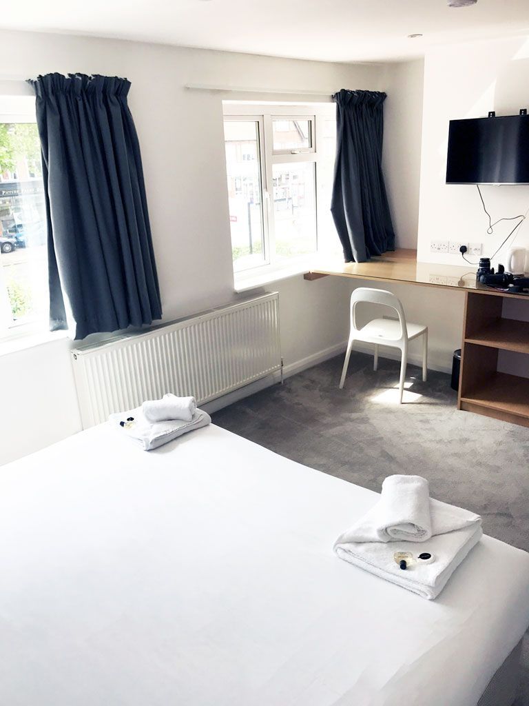 A hotel room with a bed , chair , desk and window.