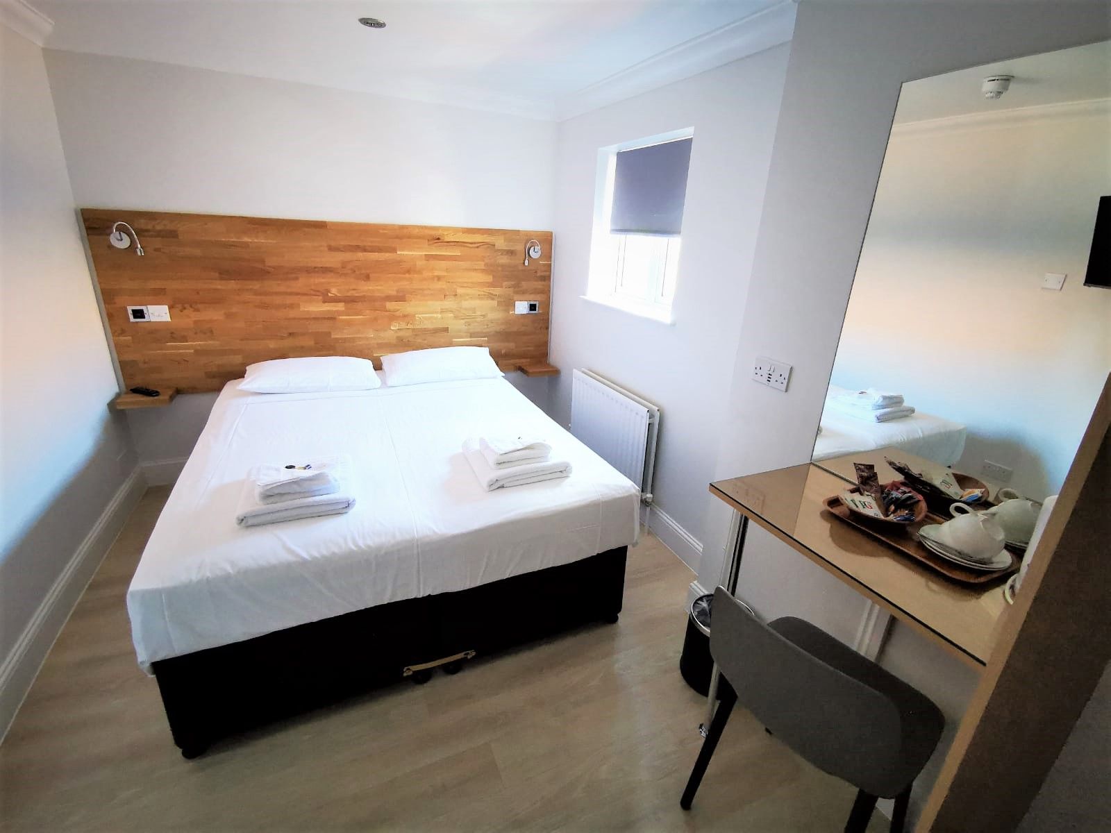 A hotel room with a bed , desk and mirror