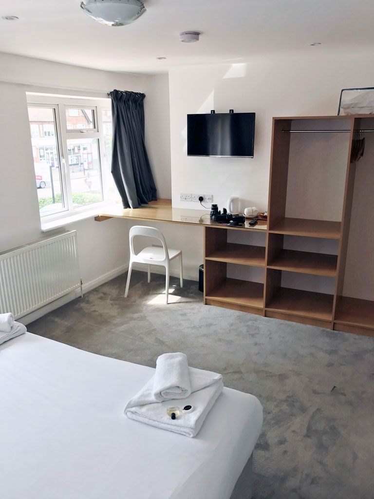 A hotel room with a bed , chair , desk and television.